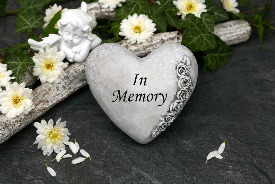 Herz mit der Inschrift „In Memory“, umgeben von weißen Chrysanthemen und einem kleinen Engel – symbolisches Trauerbild für Bestatter Bottrop