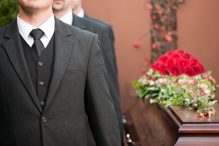 Bestatter in Dinslaken bei einer würdevollen Trauerfeier mit Sarg und Blumen.