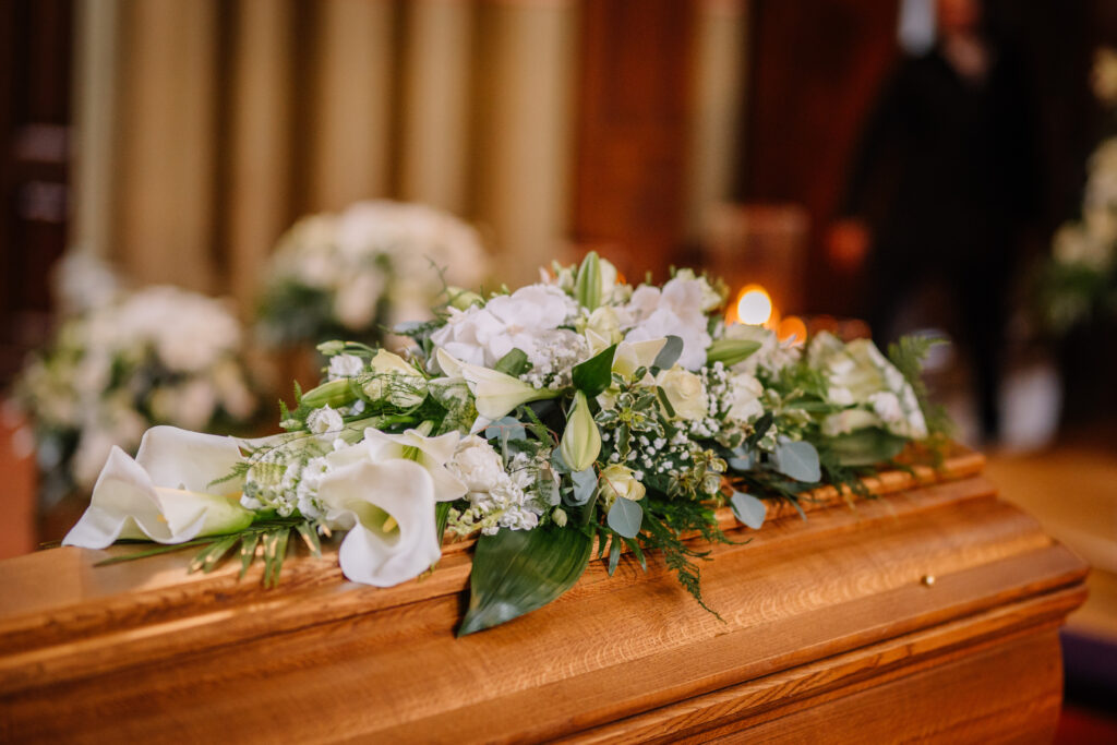 Blumengeschmückter Sarg mit Kerzen in einer Kirche als Sinnbild für eine würdevolle Trauerfeier beim Bestatter in Marl.